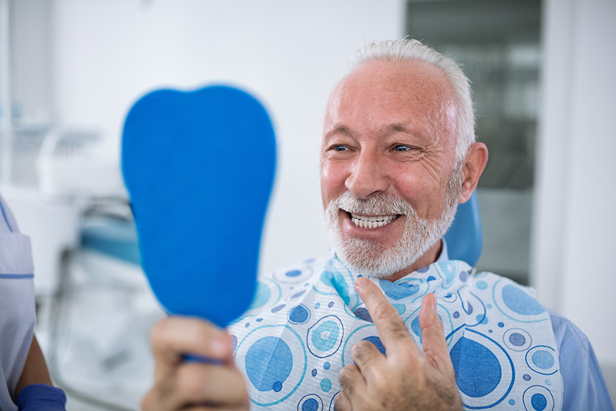 Man happy after friendly treatment and no language barrier as wide range of languages spoken at carrville family dentistry